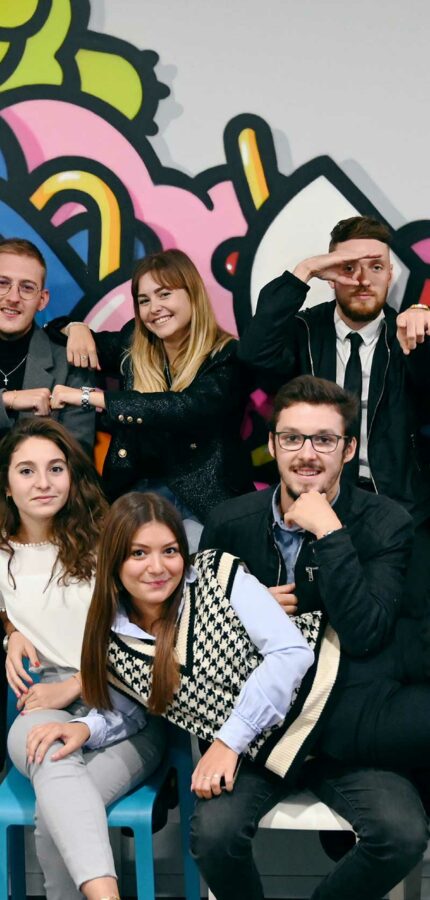 Photo d'un groupe d'un groupe d'étudiantes et étudiants en MBA, en formation initiale et en alternance, devant un graffiti.