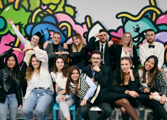 Photo d'un groupe d'un groupe d'étudiantes et étudiants en MBA, en formation initiale et en alternance, devant un graffiti.